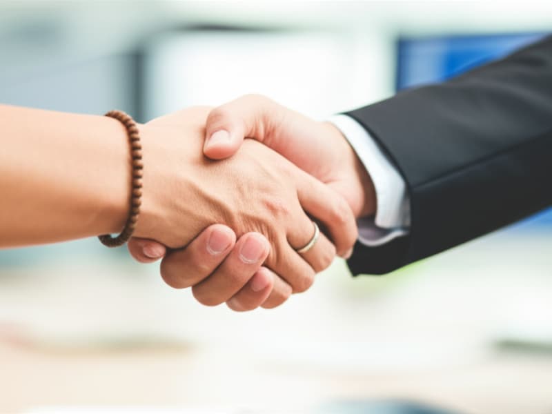 Hai bàn tay bắt chặt thể hiện sự hợp tác thành công trong thiết kế website Phật giáo và gieo duyên.